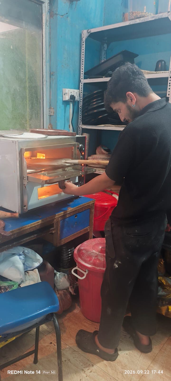 Chef sliding artisanal pizza into stone-deck oven at Singh Bites